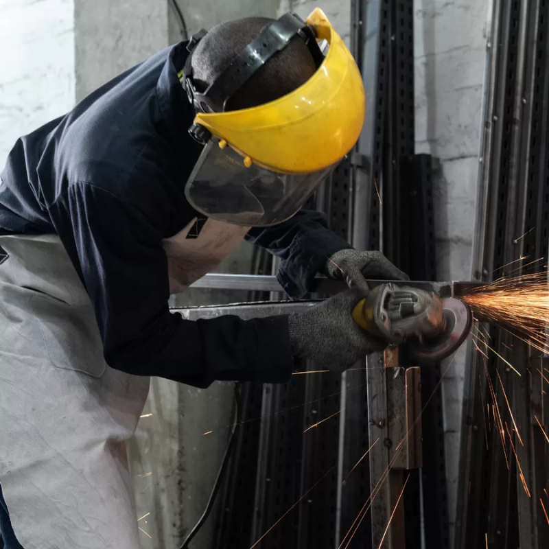 Un Alma de Acero de Estanterías Medellín usando una pulidora para fabricar una góndola metálica
